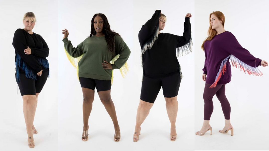  The image shows four plus-size models in oversized sweaters with colorful fringe details, styled with biker shorts or leggings for a chic, confident look.