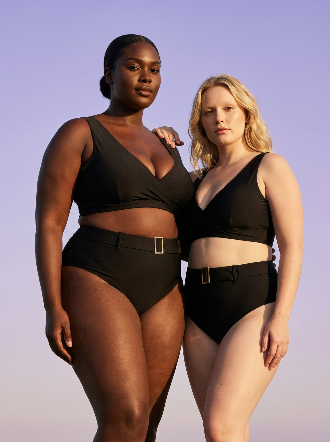 Two women wearing black swimsuits against a purple sky.